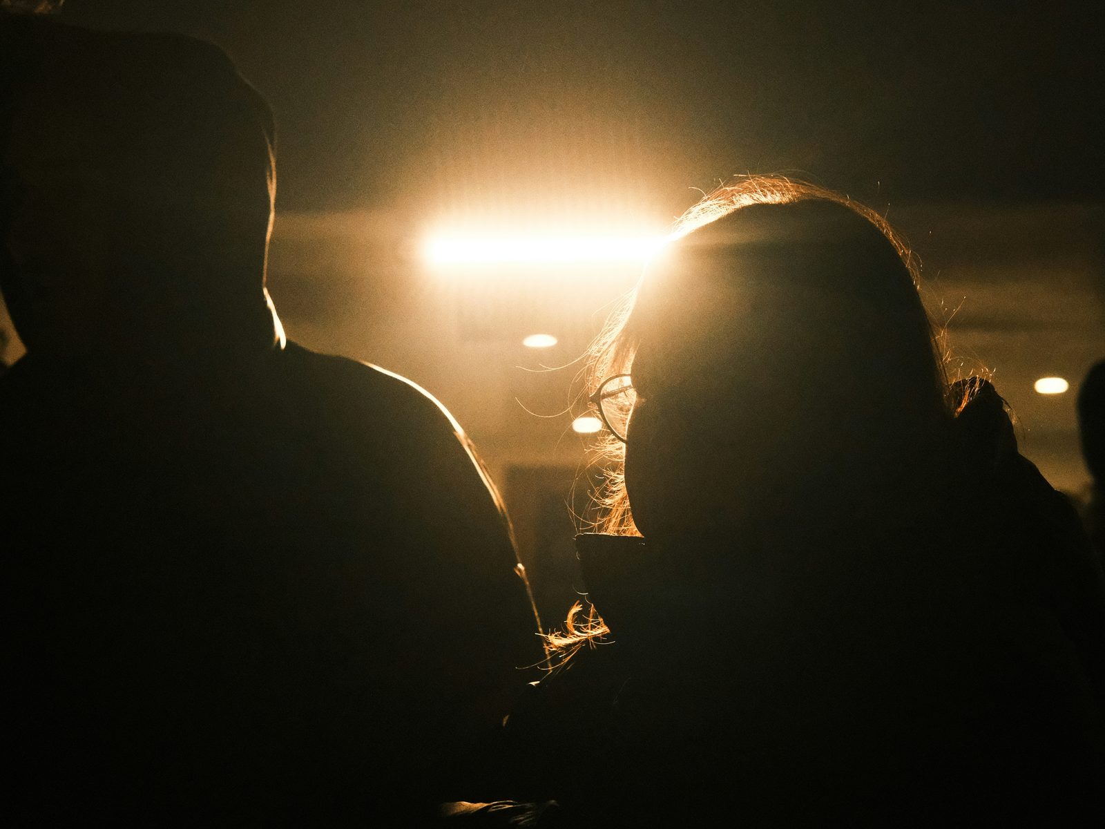 Audience members in silhouette against stage light